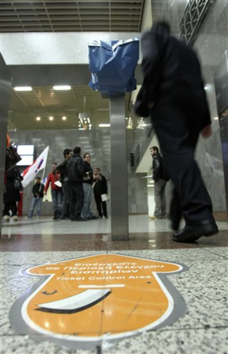 A passenger passes a covered ticket machine with a plastic bag during a protest by PAME, a Communist Party-backed labor union, at the Syntagma Metro station in Athens.